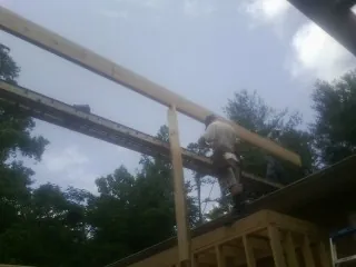Carpenter setting a ridge beam over a new addition frame — Ice Dam Removal by Roofing Brothers in Nova