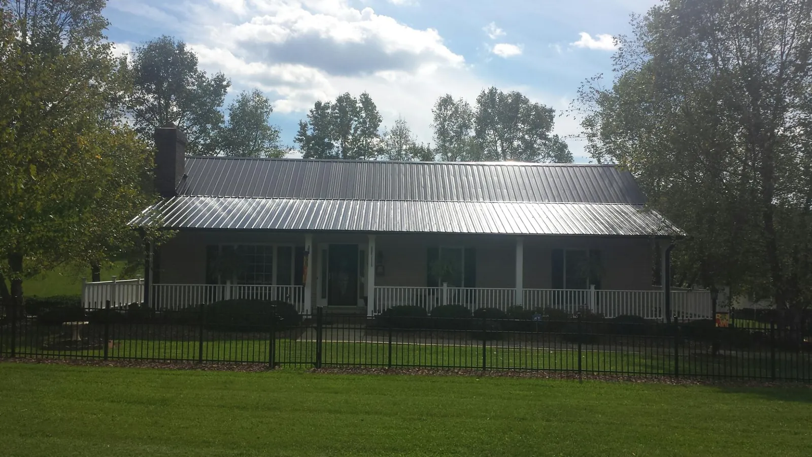 Gray metal roof on a brick ranch with a full width front porch — Gutter Guard Installation work by our crew in Nova