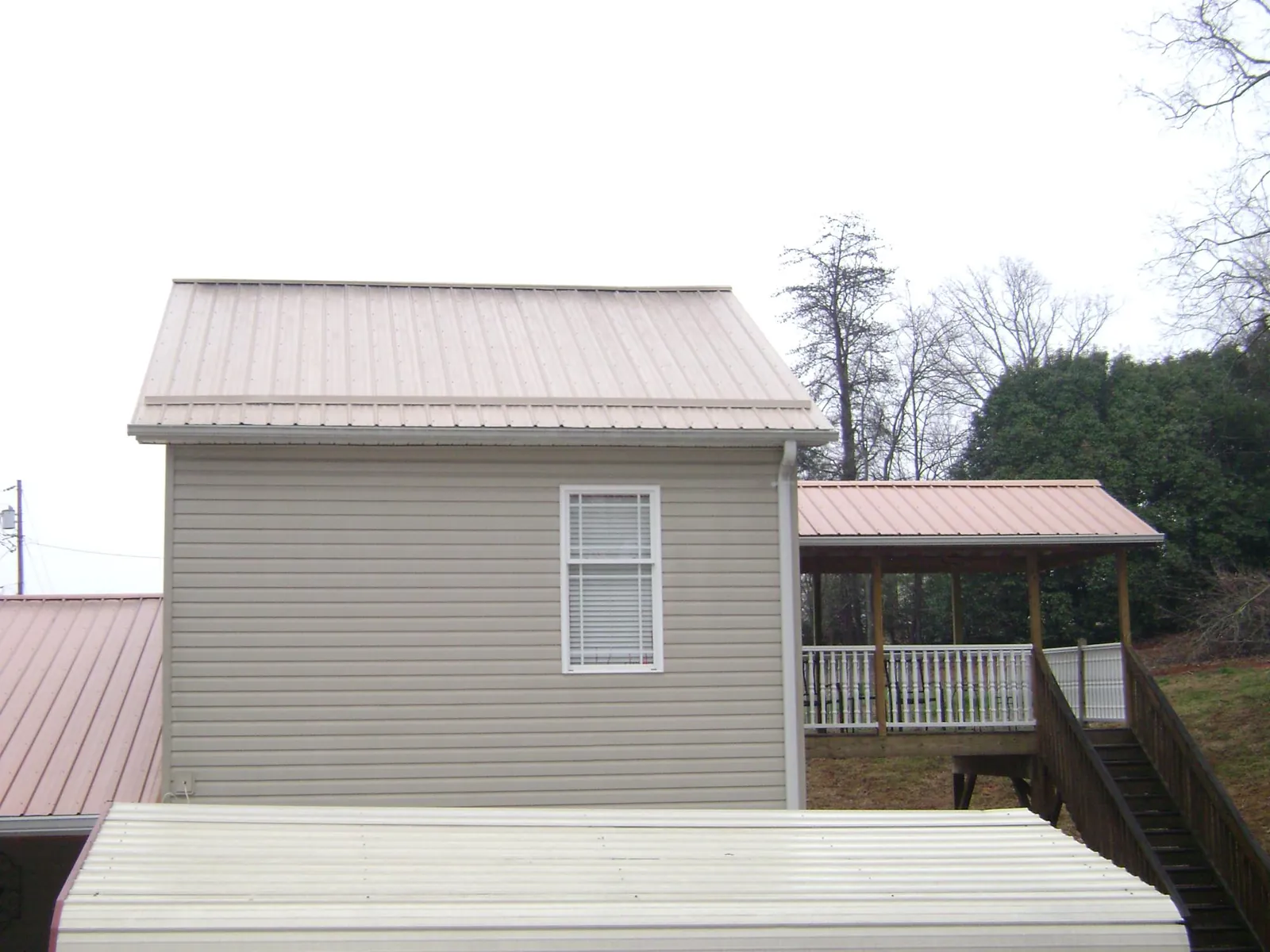 Tan metal roofs on a two story addition and attached porch, from a Roof Replacement job in Nova